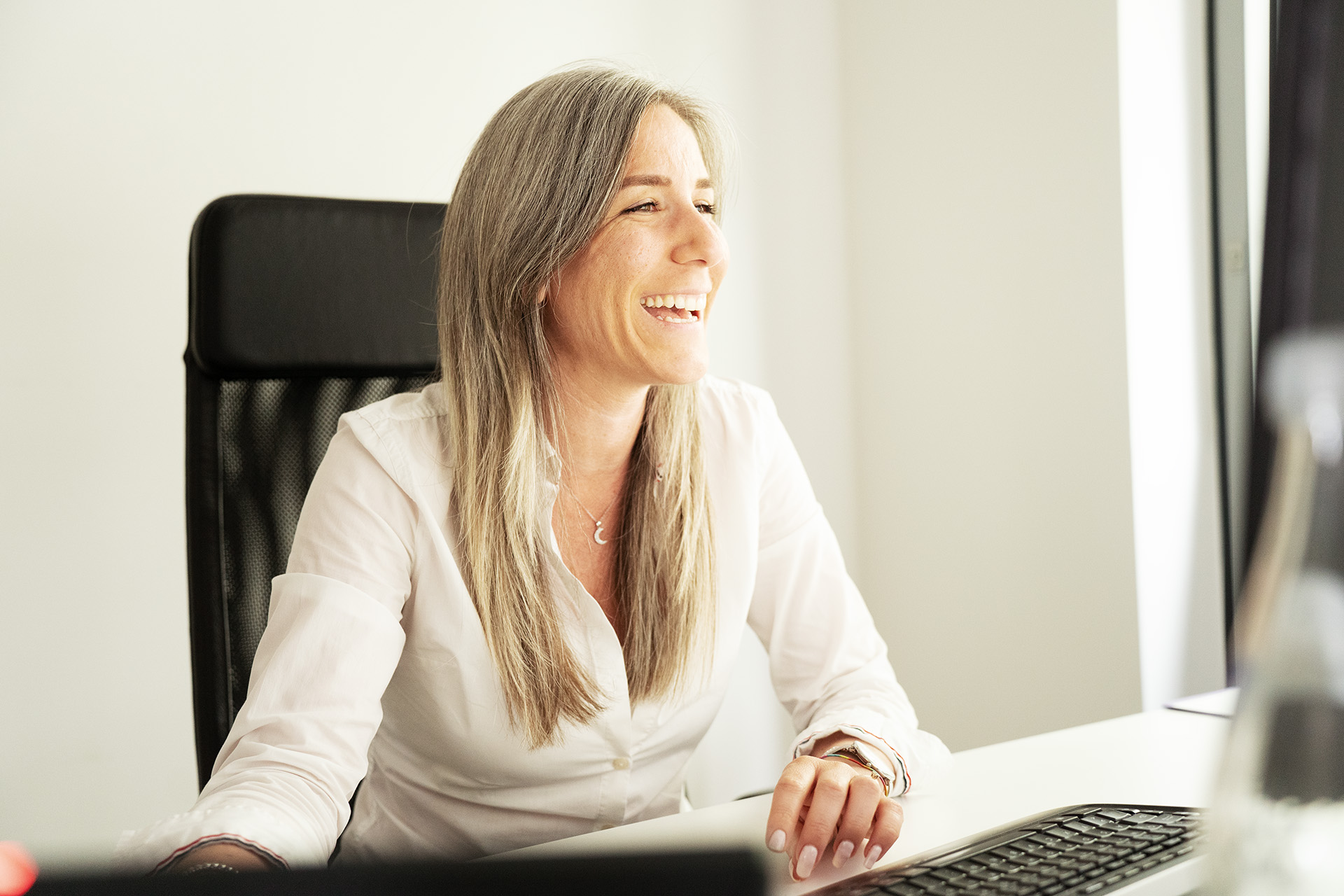 Mitarbeiterin lachend am Schreibtisch