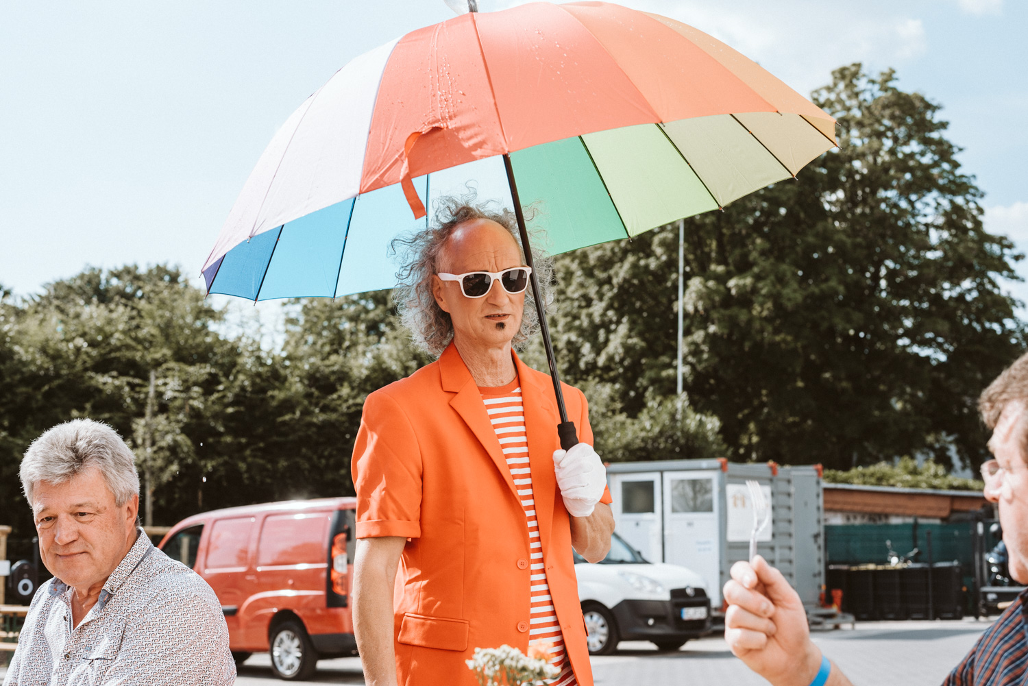 Teamevent bunt gekleideter Mann mit buntem Regenschirm