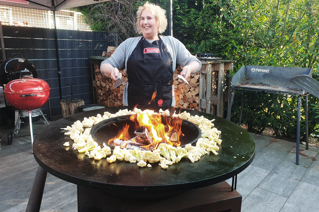 Kochevent Frau steht draußen an einer Feuertonne